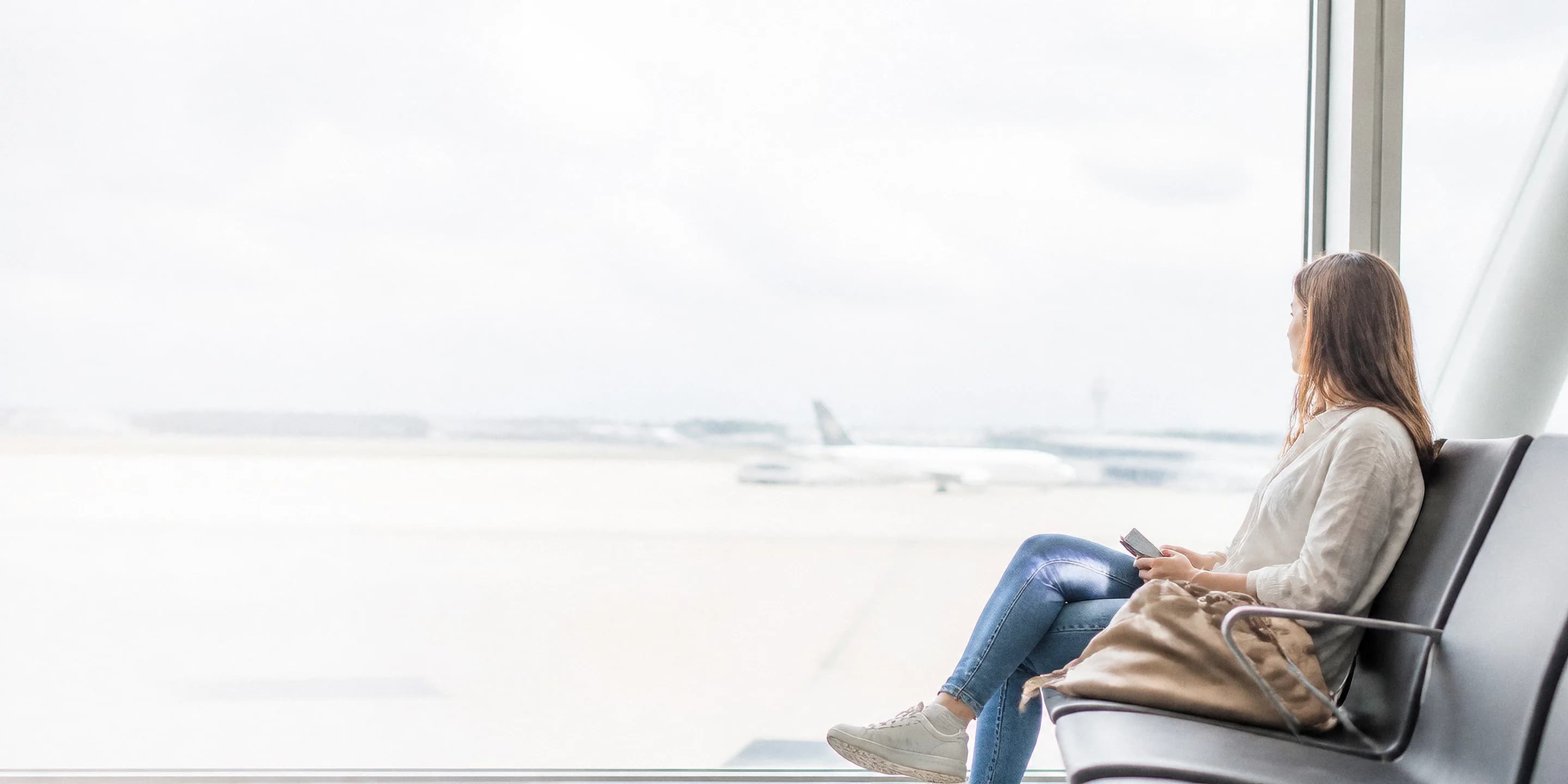 Passagère sereine dans une salle d'embarquement lumineuse, regardant les avions